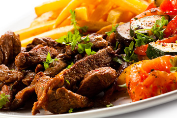 Grilled meat with French fries and vegetables