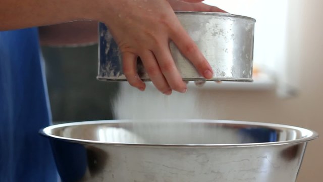 Girl sifts the flour through a sieve