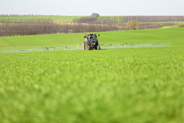 Tractor spraying a green field on a farm
