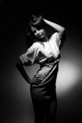 Obraz premium Beautiful girl in a white dress on a dark background.