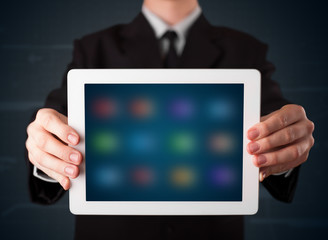 Businessman holding a white modern tablet with blurry apps