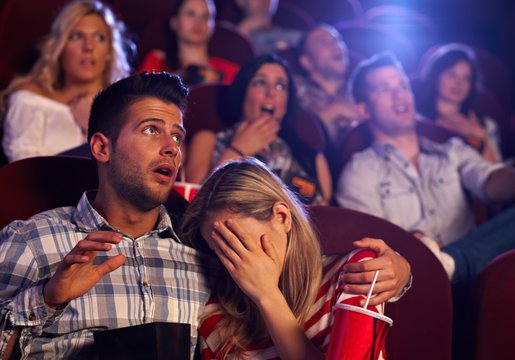 Young couple watching horror in movie theater