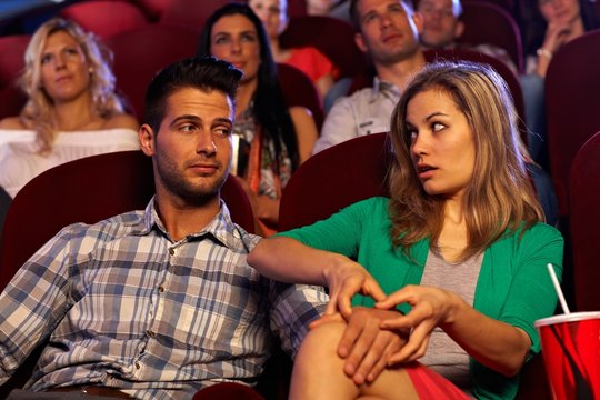 Young man molesting girl in cinema on first date
