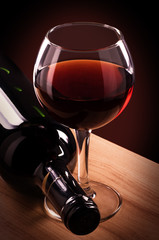 Rode wijnglas en fles op een houten tafel