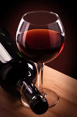 Poster Wijn Rode wijnglas en fles op een houten tafel