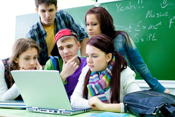 group of young students studying in the classroom with a laptop