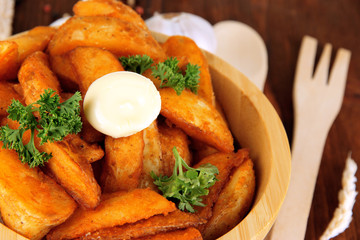 Appetizing village potatoes in bowl on wooden table close-up