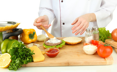 Female hands preparing cheeseburger, isolated on white