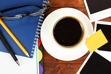 Cup of coffee on worktable covered with photo frames close up