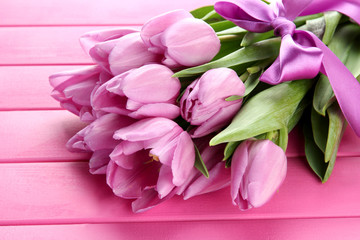 Fototapeta na wymiar Beautiful bouquet of purple tulips on pink wooden background