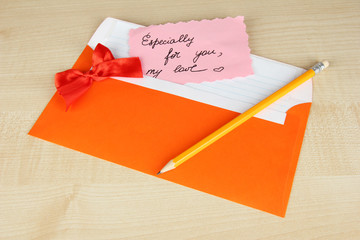 Note in envelope with pencil on wooden background