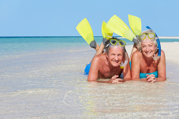 Senior Couple With Snorkels Enjoying Beach Holiday
