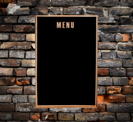 Empty menu board hanging on grunge brick wall