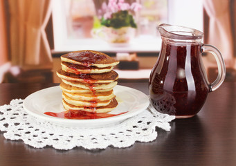 Sweet pancakes on plate with jam on table in room