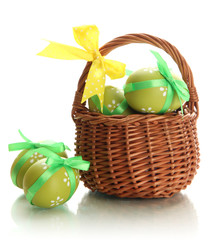 Bright easter eggs with bows in basket, isolated on white