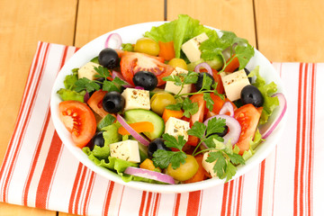 Fresh salad in plate on wooden table