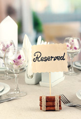 Reserved sign on restaurant table with empty dishes and glasses