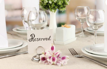Reserved sign on restaurant table with empty dishes and glasses