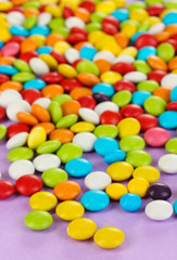 Fototapeta na wymiar Kolorowe cukierki na liliowym tle