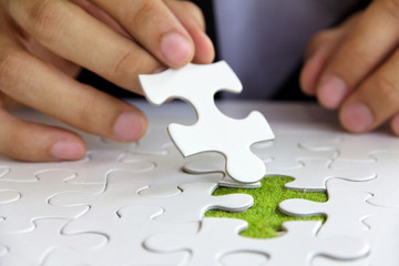 business man hand holding a puzzle piece, green space concept