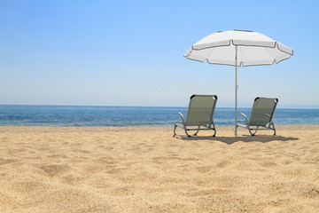 Umbrella and lounge chairs on idyllic beach
