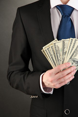 Business man holds lot of money on black background