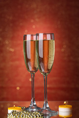 Two glasses of champagne on bright background with lights