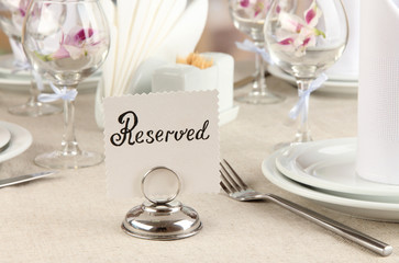 Reserved sign on restaurant table with empty dishes and glasses