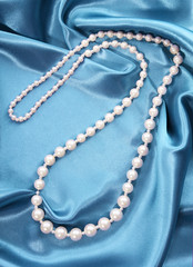 pearl necklace on turquoise silk fabric, luxury