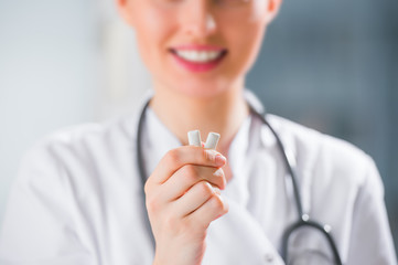 Young female dentist doctor holding chewing gum and smiling. Ora