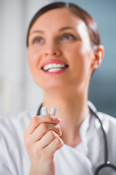 Young female dentist doctor holding chewing gum and smiling. Ora