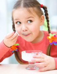 Little girl is eating ice-cream in parlor