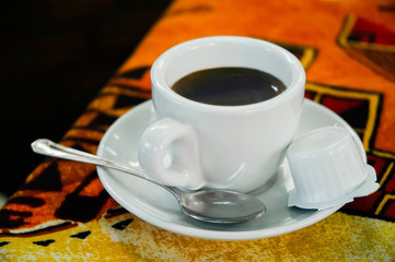 A warm cup of black coffee with a bucket of milk