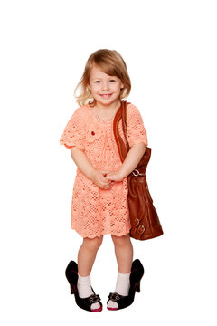 Happy girl with bag wearing her mother's shoes and jewelry