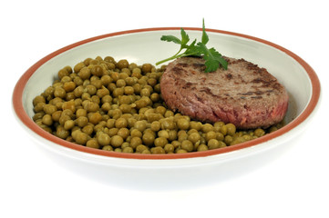 Une assiette de petits pois et un steak haché