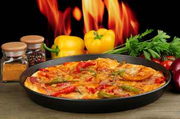 Tasty pepperoni pizza in pan with vegetables on flame