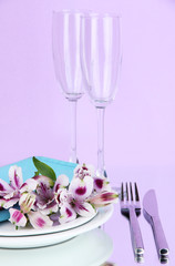 Festive table setting with flowers on lilac background