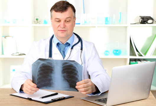 Medical doctor analysing x-ray image at desk