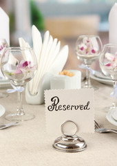 Reserved sign on restaurant table with empty dishes and glasses
