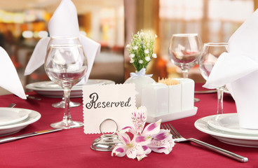 Reserved sign on restaurant table with empty dishes and glasses