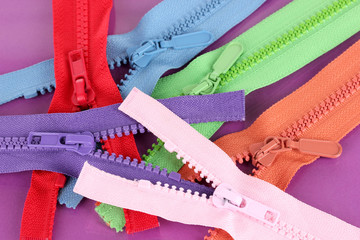 Multicolored zippers on purple background