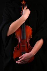 Violin in hands on black background