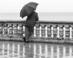 Hombre con paraguas apoyado en balustrada