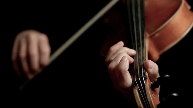 Woman playing violin over dark background
