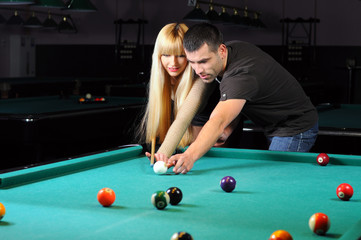 Young couple playing snooker in a billiard club