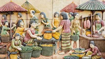 Stone carving of Thai rural fresh market on temple wall