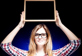Woman with nerd glasses holding wooden frame over her head