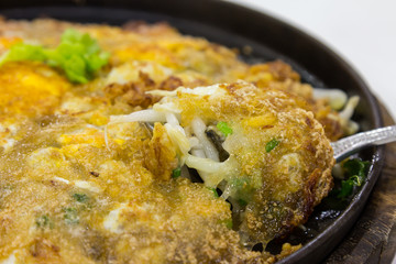 Fried oysters with egg and scoop on hot plate