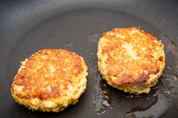 Two Crab Cakes Browning in Saute Pan
