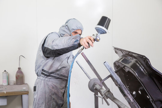 Car body painter spraying paint on bodywork parts